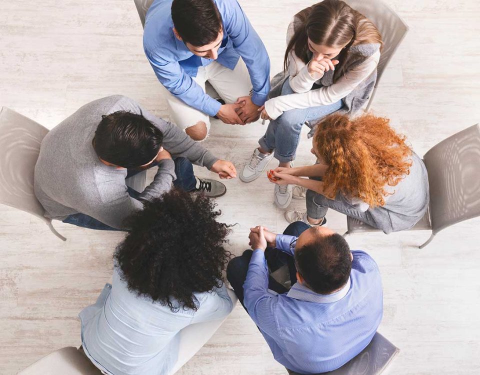 six people sitting on chairs talking in a group