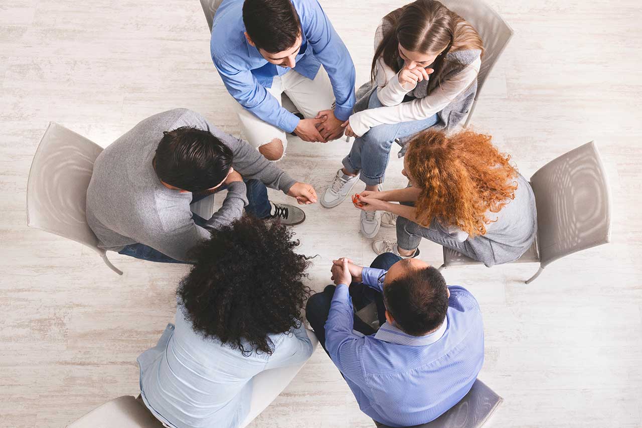 six people sitting on chairs talking in a group