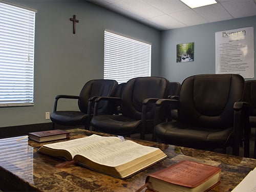 Faith-based group therapy room with Bibles on the table and a cross on the wall