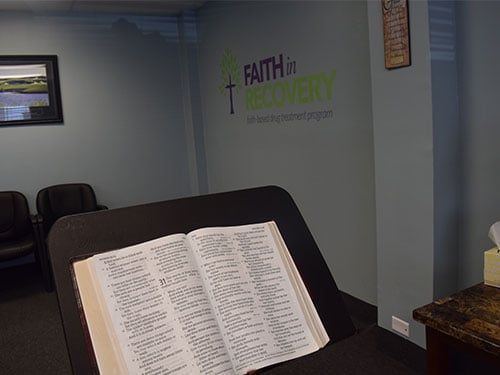 Bible displayed in a counseling room with 'Faith in Recovery' signage on the wall