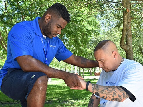 Banyan staff member and client praying together outdoors at Banyan Treatment Center's faith-based program